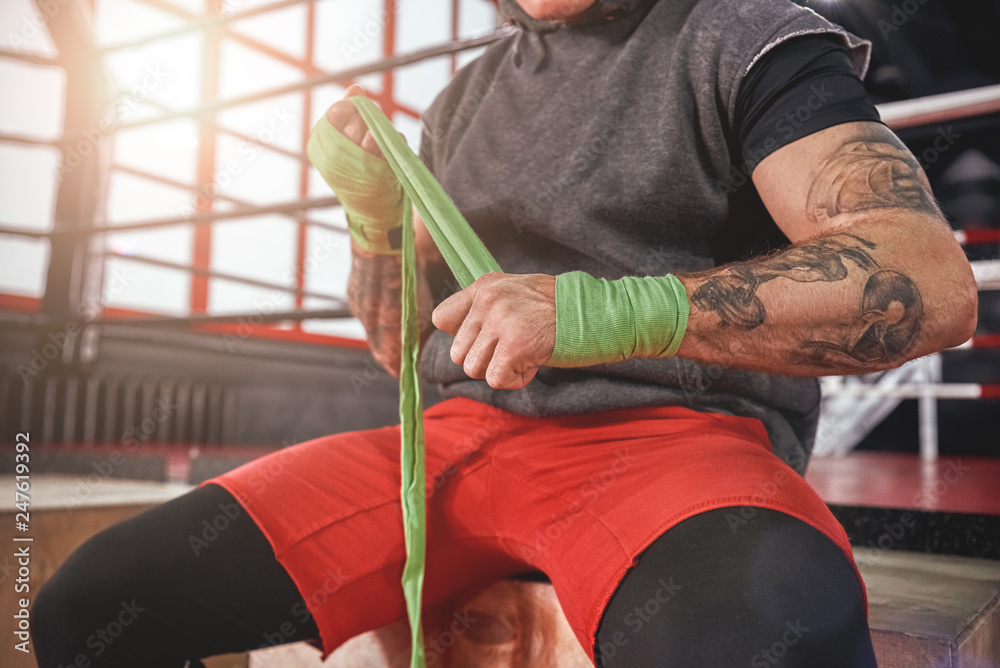He is a new champion. Strong tattooed athlete in sports clothing wrapping  hands with green boxing wraps, close-up of strong hands and fist ready for  fight Stock Photo | Adobe Stock