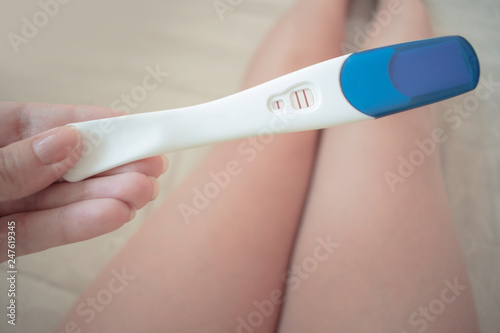 Pregnancy test in female hand on blurred background. The result is positive with two strips. Pregnant woman.