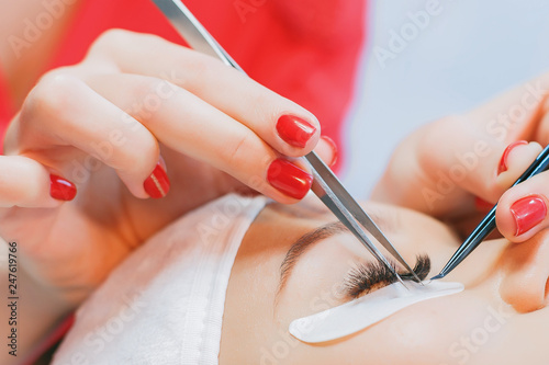 Eyelash Extension Procedure. Woman Eye with Long Eyelashes. Beautiful young girl tweezing her eyebrows in a beauty salon. Eyebrow Correction. Beauty Concept. Permanent Makeup. Microblading brow.
