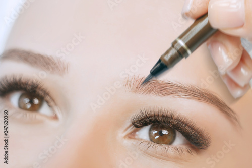 Beautiful young girl with long eyelashes tweezing her eyebrows in a beauty salon. Eyebrow Correction. Beauty Concept. Permanent Makeup. Microblading brow. Beautician Doing brows Tattooing.