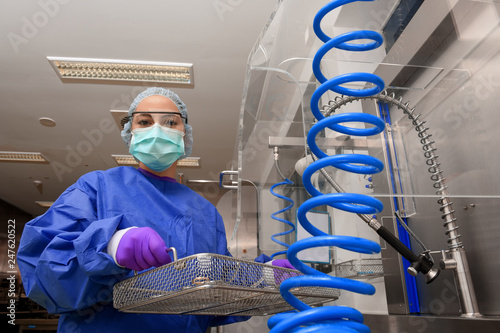 A young woman works in a hospital as a  medical hygiene assistant. She is dressed  in special medical hygiene clothing and  carries out hygiene disinfecting and logistic tasks.