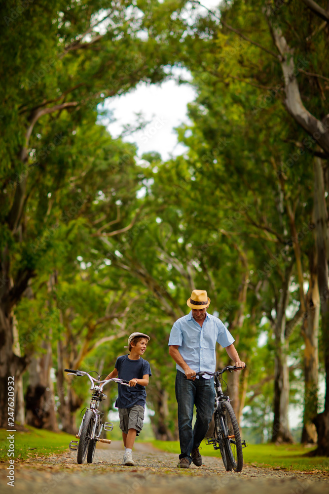 Father and son walking and pushing their bicycles. Father and son walking and pushing their bicycles.