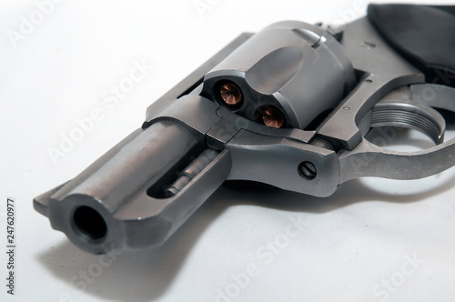 A close up of a stainless snub nose 357 magnum revolver on it's side loaded with hollow point bullets on a white background