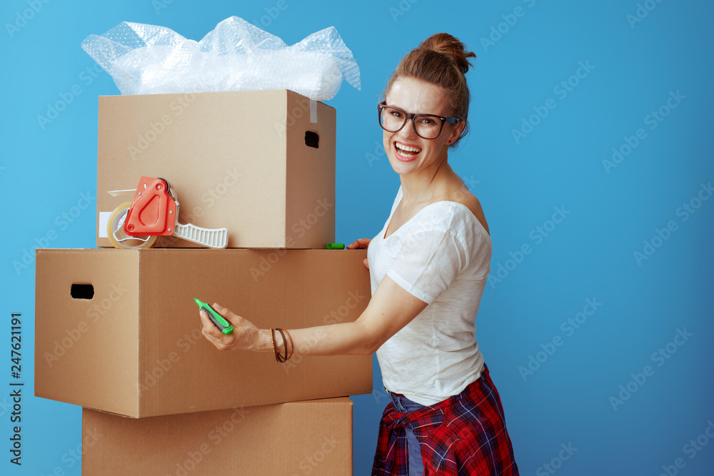 smiling modern woman signs cardboard box on blue smiling modern woman signs cardboard box on blue