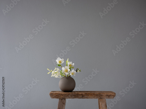 Kleine runde Keramikvase auf einem alten Vintage-Schemel mit Blumen im Frühling