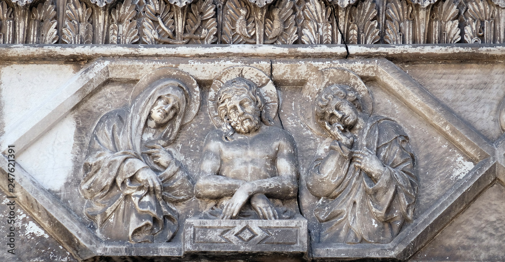 Jesus bound with the Virgin Mary and St. John on the portal of the Cathedral of S.Martino in Lucca, Italy Jesus bound with the Virgin Mary and St. John on the portal of the Cathedral of S.Martino in Lucca, Italy