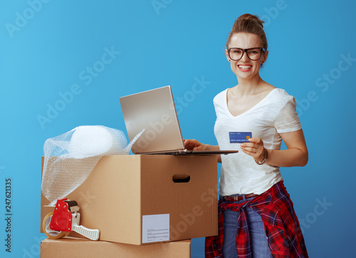 woman near cardboard box with laptop and credit card on blue