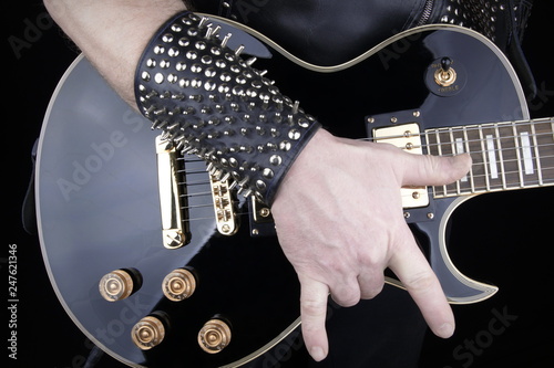 Guitarist.Closeup of electrical guitar fingerboard.Hand of rocker in leather  bracelet.Rock & roll, heavy metal,gothic,punk,horns sign and fist.Hard style.Rivets accessories