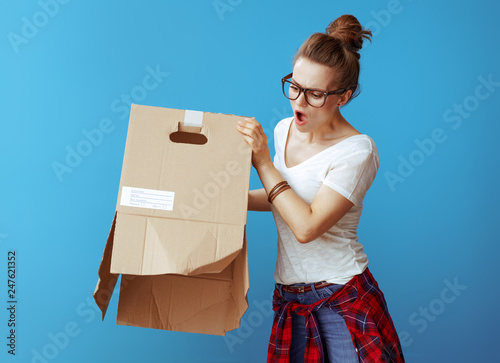 woman shakes out something from old cardboard box on blue