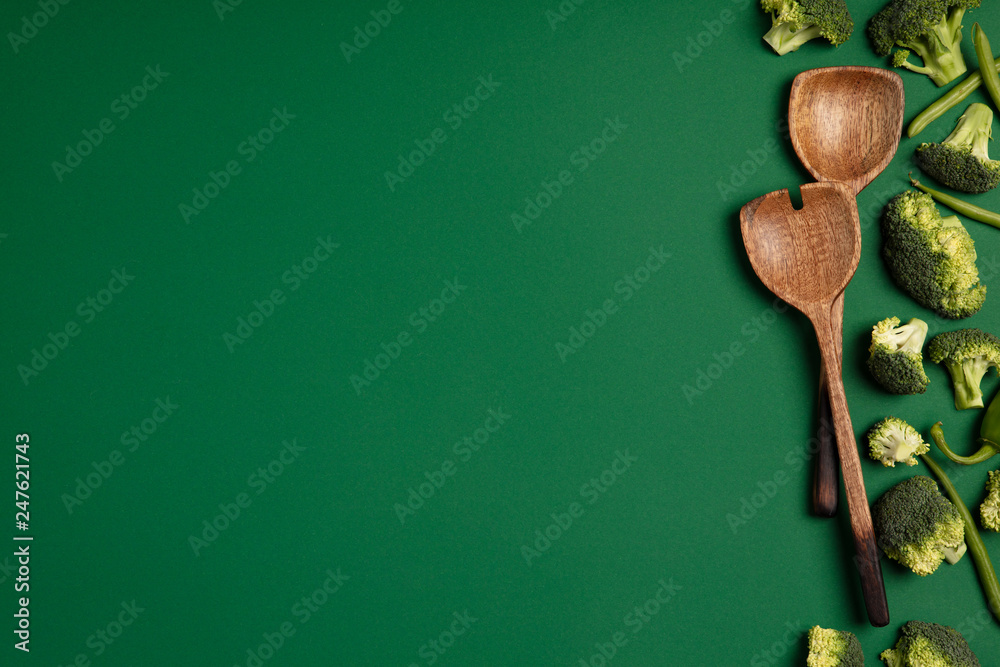 Broccoli and serving spoons on a green background. Broccoli and serving spoons on a green background.