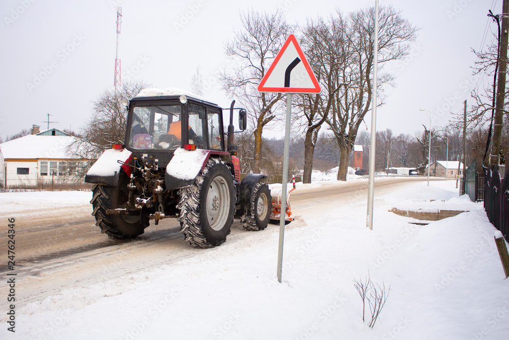 Fototapeta premium red tractor clears the road from snow