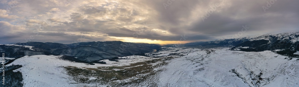 Aerial view of a gold sunset over winter snow.Panorama.