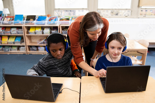 Teacher helping students with laptop computers