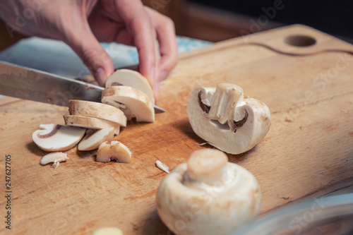 Girl cook is cutting mushrooms on a wooden Board