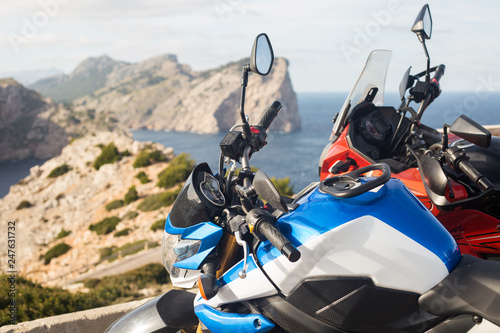 two motorcycles with beautiful landscape behind: rocky sea coast