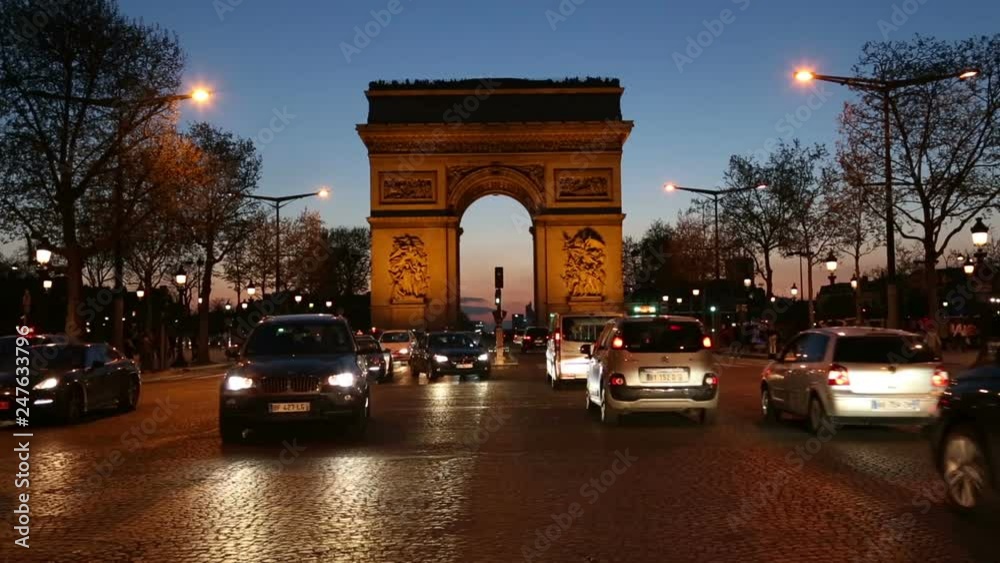 Traffic driving along the Champs-Elysees at sunset with the Arc de Triomphe in background, Paris, France Traffic driving along the Champs-Elysees at sunset with the Arc de Triomphe in background, Paris, France
