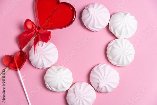 marshmallow and candy hearts on a pink background with copy space