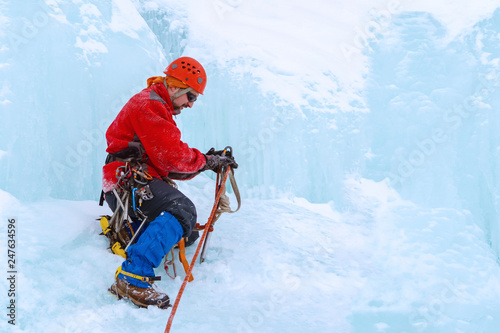 climber prepares equipment to climb the ice wall