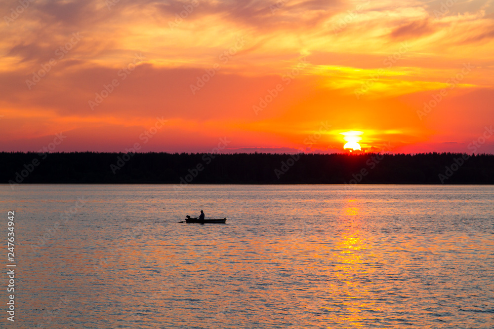 Fishermen float on a lake at sunset