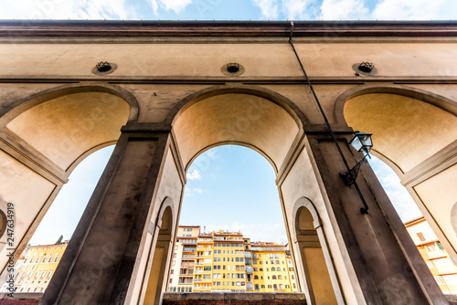 Florence, Italy Firenze orange yellow colorful buildings on street called Lungarno degli Acciaiuoli during summer in Tuscany with wide angle view of Corridoio Vasariano photo