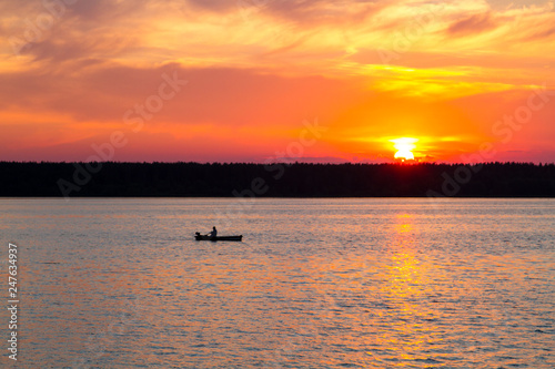 Fishermen float on a lake at sunset © Alexey Kartsev
