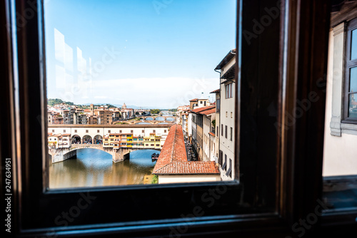 Florence, Italy Firenze high angle view orange colorful buildings and Arno river during summer morning sunrise in Tuscany with Ponte Vecchio through window photo