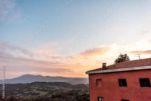 Chiusi sunset evening in Umbria  Italy with red house on mountain countryside rolling hills and colorful picturesque city and sunlight clouds