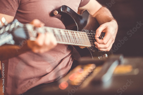Close up hand of young man playing on a professional, black electric guitar, music  instrument, entertainment (color toned image)