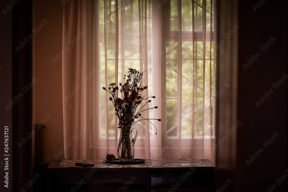 Flower arrangement bouquet in dark rustic house home by window on windowsill silhouette and curtains on table in farm cottage house Flower arrangement bouquet in dark rustic house home by window on windowsill silhouette and curtains on table in farm cottage house