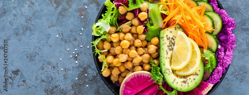 Salad Buddha bowl with fresh cucumber, avocado, watermelon radish, raw carrot, lettuce and chickpea for lunch. Healthy vegetarian food. Vegan vegetable dish. Top view. Banner
