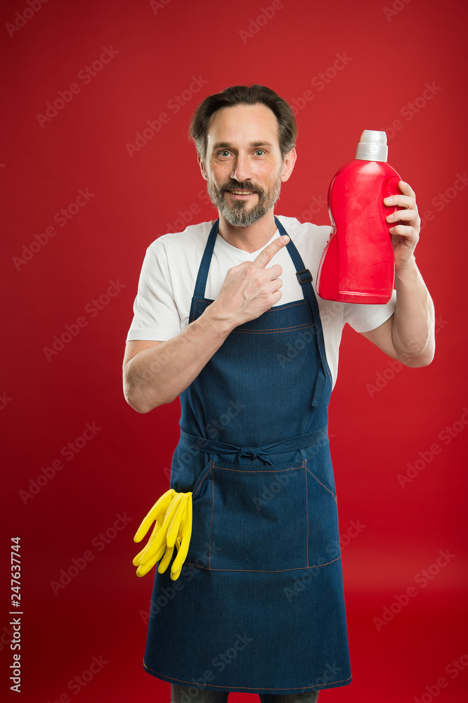 On guard of cleanliness and order. Cleaning service and household duty. Man in apron with gloves hold plastic bottle liquid soap chemical cleaning agent. Cleaning day today. Bearded guy cleaning home On guard of cleanliness and order. Cleaning service and household duty. Man in apron with gloves hold plastic bottle liquid soap chemical cleaning agent. Cleaning day today. Bearded guy cleaning home