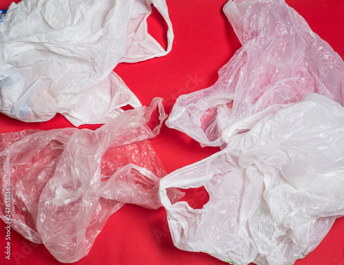 plastic bags and bottles on a red background with space for text..ecology mockup photo