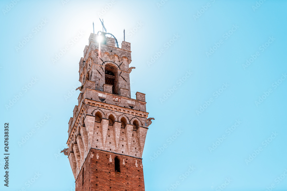 Siena, Italy Piazza Street in historic medieval old town village in Tuscany with isolated closeup of blue sky with sun and tower