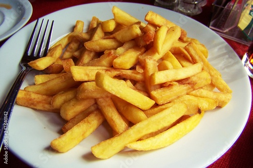 Golden French Fries, on white circle plate with fork. 