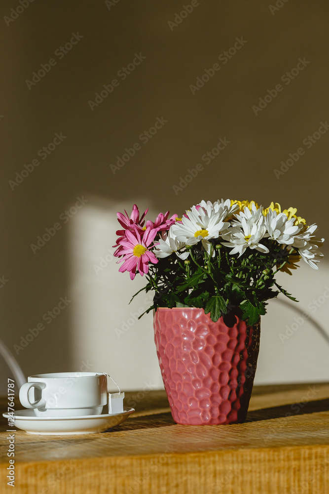 A cup of tea on a table next to a beautiful flower pot.