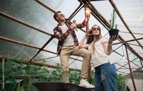 Happy and young gardeners working in a greenhouse