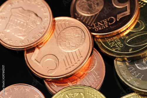 A macro image of an assortment of Euro coins on a reflective black background