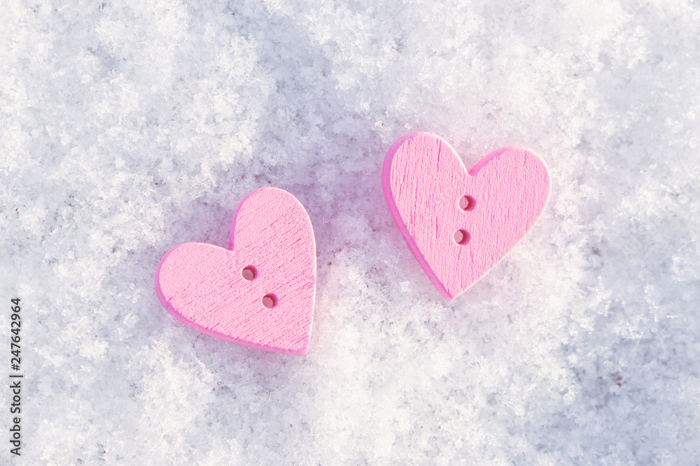Two pink wooden hearts on white snow. View from above. Background to the Valentine's day and wedding.