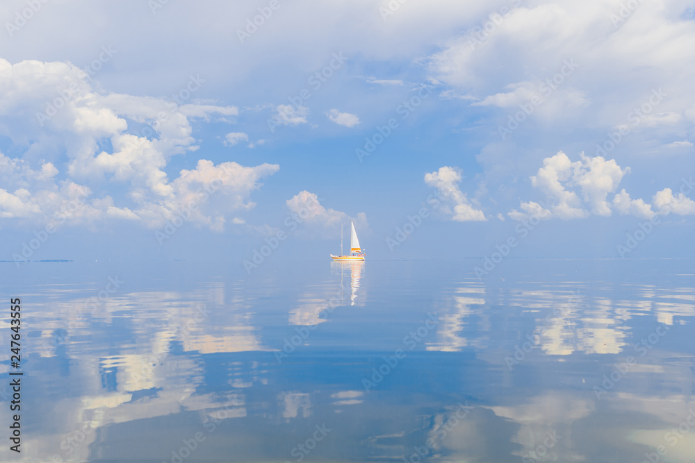 Obraz premium Sailboat in sea in sunny day on fabulous fairy tale picturesque seascape with clouds reflected in water. Luxury yacht summer adventure. Active vacation on mediterranean sea. Tourism and travel.