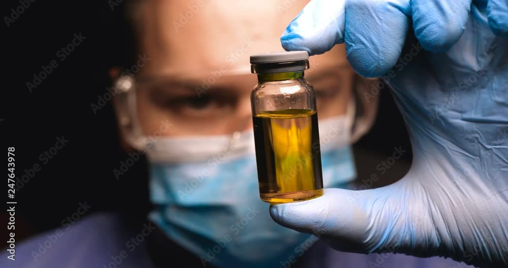 Male doctor in work uniform wearing gloves with goggles goggles examines in vitro analysis. Concept of: Proffessional doctor, Urine tests, Laboratory assistant, All protective kit.