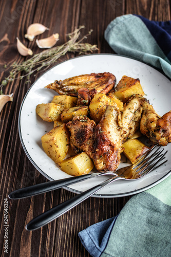 Baked chicken wings with potatoes and garlic on a rustic background