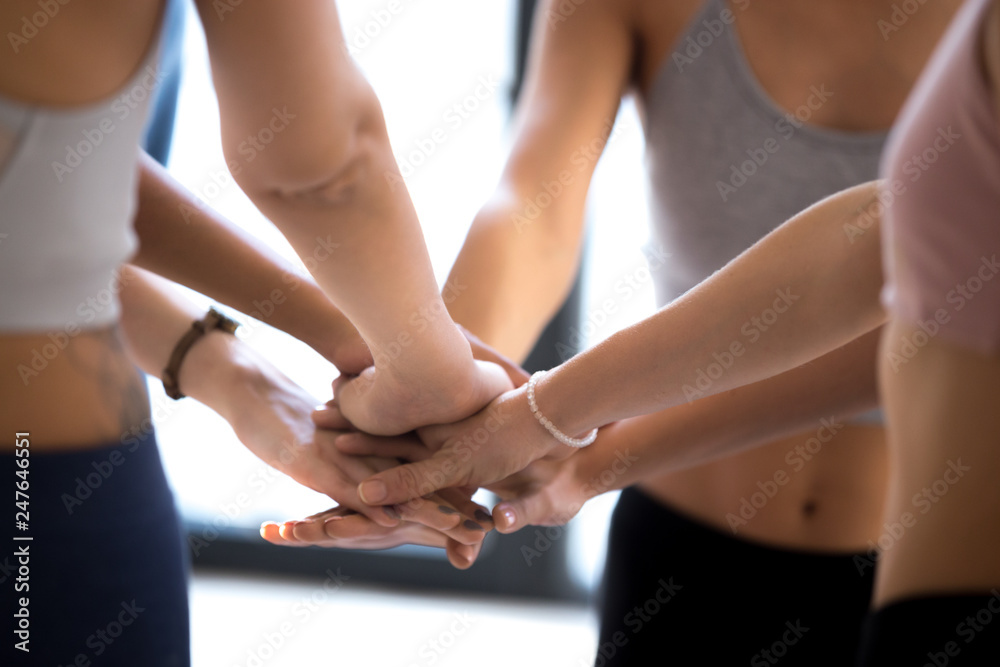 Sportive women stack hands showing team spirit at training Sportive women stack hands showing team spirit at training