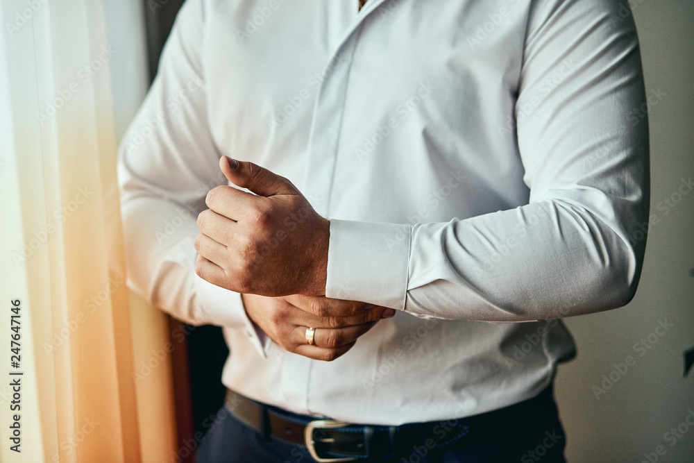 Fototapeta premium businessman dresses white shirt, male hands closeup,groom getting ready in the morning before wedding ceremony. Men Fashion