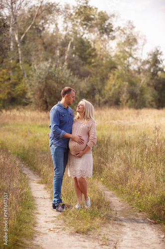Portrait of pretty young pregnant woman with her young husband walking in park in sunny day. Family. Maternity. Happiness. Health. Mothers day © AnnKot