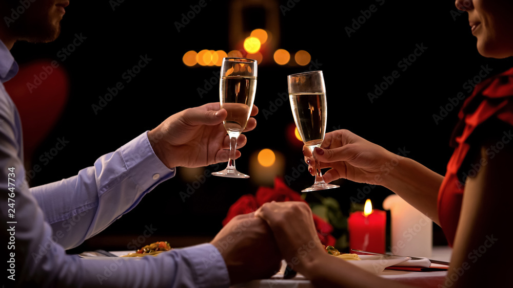 Nice couple holding hands, drinking champagne during romantic date, anniversary - obrazy, fototapety, plakaty 