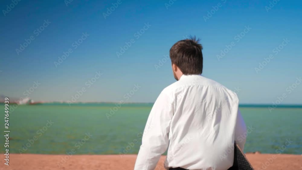 The businessman runs to the sea with a kitesurf board The businessman runs to the sea with a kitesurf board