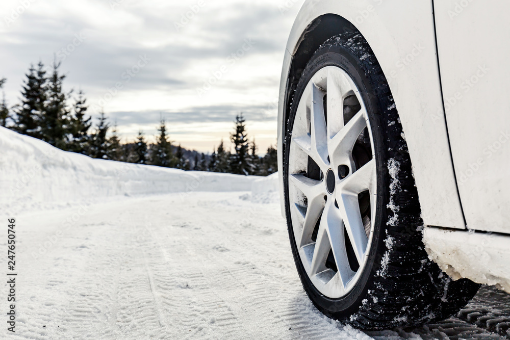 The wheel of a car on a snowy mountain road in the cold winter
