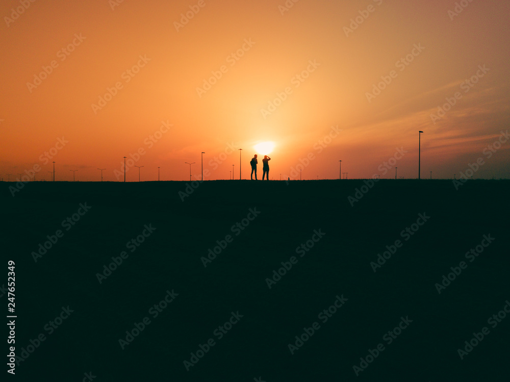 Due sagome di persone al tramonto giallo