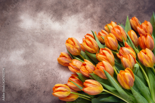 Orange tulips bouquet on brown watercolor background. Copy space, top view. Holiday background, greeting card