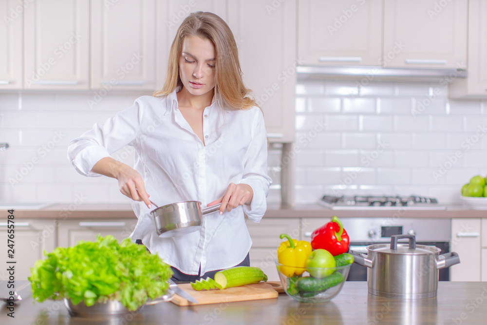 Happy young girl preparing healthy food in the kitchen